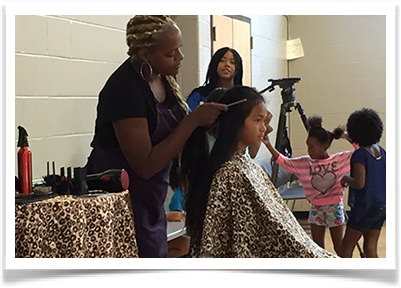 A young girl enjoys getting a new style at the hair cut event.